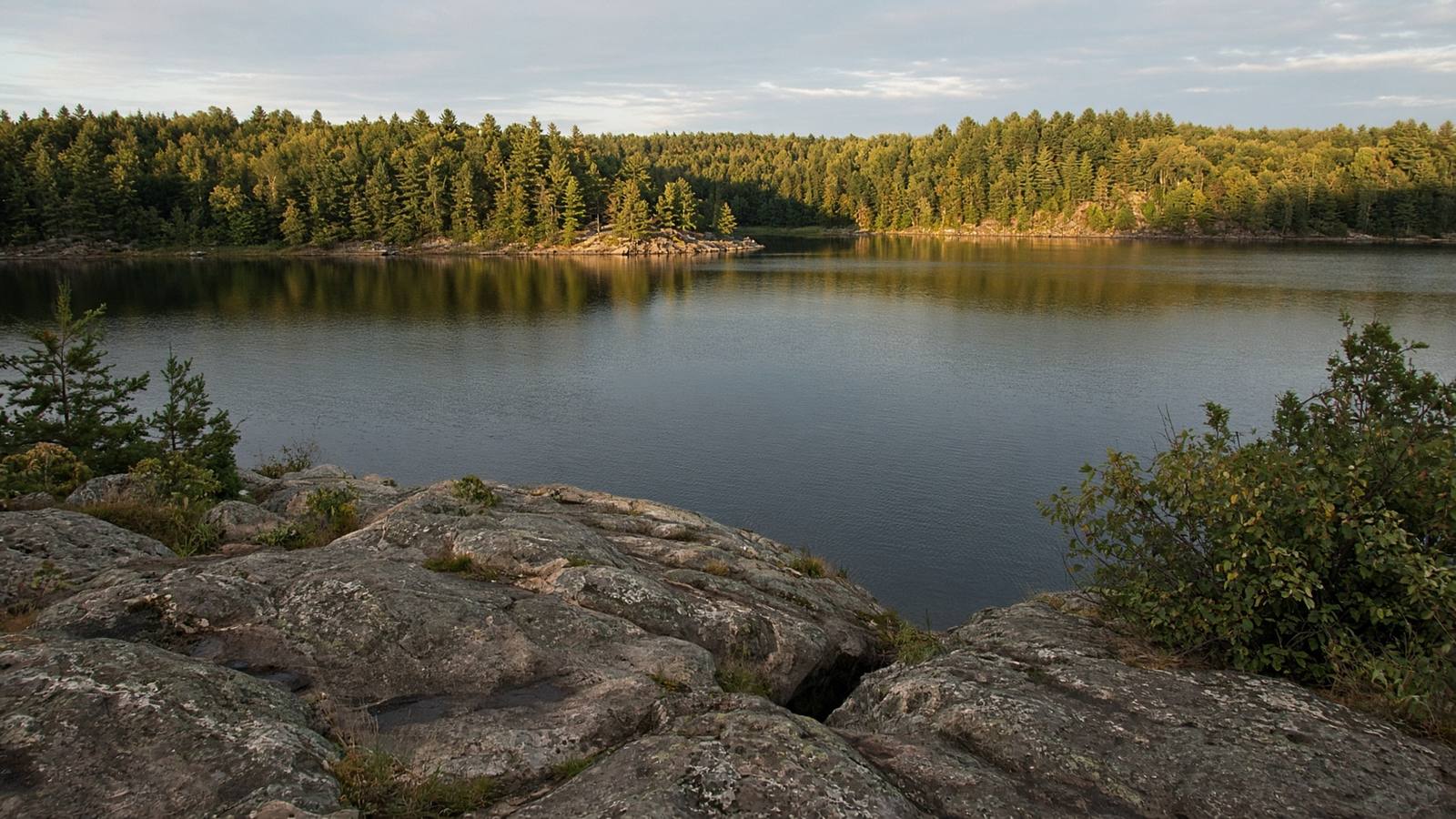A quiet inland lake seen from a low rocky rise in Northern Ontario
